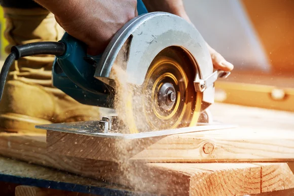 Hand schneidet Holz mit Kreissäge