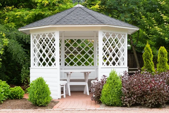 Weißer Gartenpavillon mit Tisch und Bänken
