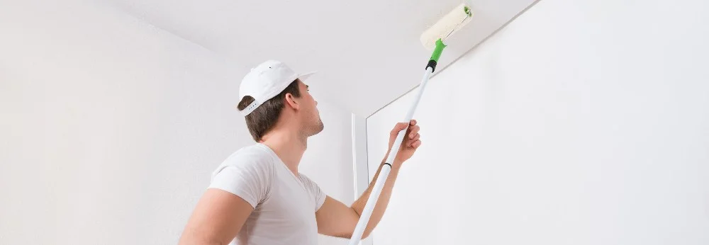 Person streicht Decke mit Farbrolle