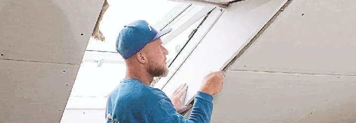 Eine Person verkleidet Dachfenster.