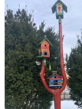 Drei bunte Vogelhäuser auf einem roten Stamm